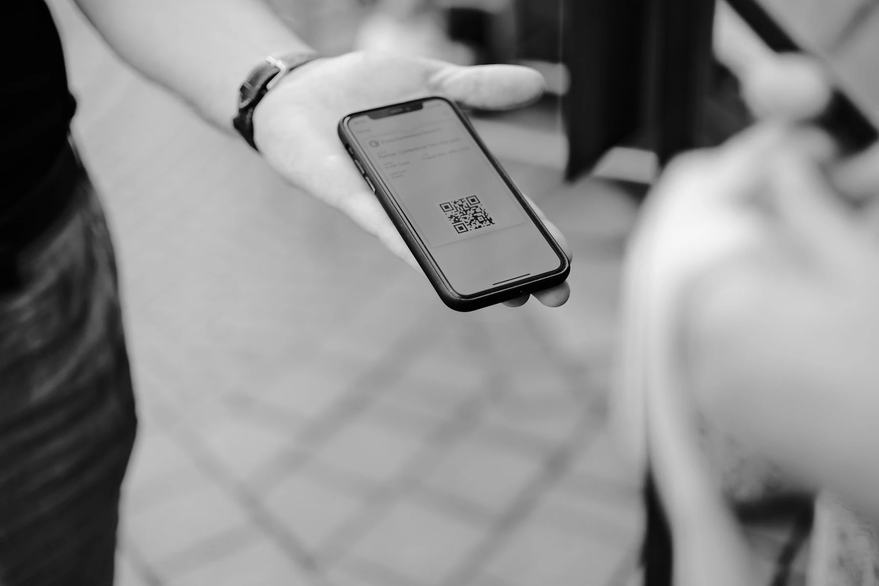 Person holding a phone displaying a QR-code ticket